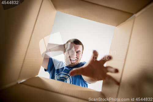 Image of Man unpacking and opening carton box and looking inside