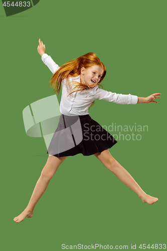 Image of Young happy caucasian teen girl jumping in the air , isolated on green background