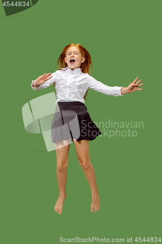 Image of Young happy caucasian teen girl jumping in the air , isolated on green background