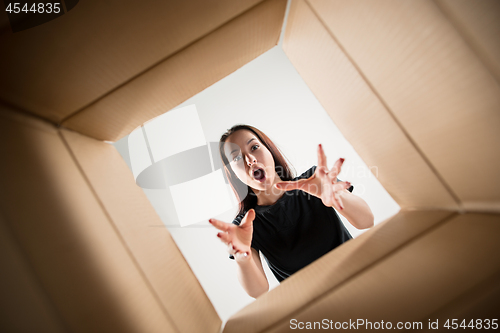 Image of Woman unpacking and opening carton box and looking inside