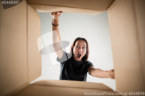 Image of Woman unpacking and opening carton box and looking inside