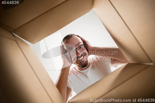 Image of Man unpacking and opening carton box and looking inside