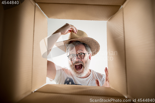 Image of Man unpacking and opening carton box and looking inside