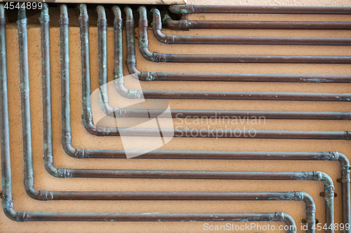 Image of some copper tubes outside on a wall