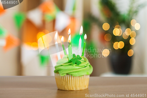 Image of green cupcake with six burning candles on table