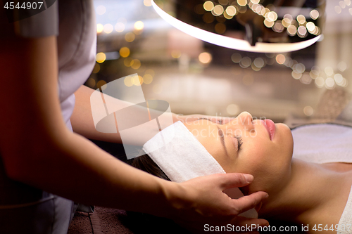 Image of beautician doing face massage to woman at spa