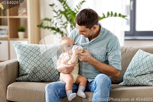 Image of father and baby drinking from bottle at home