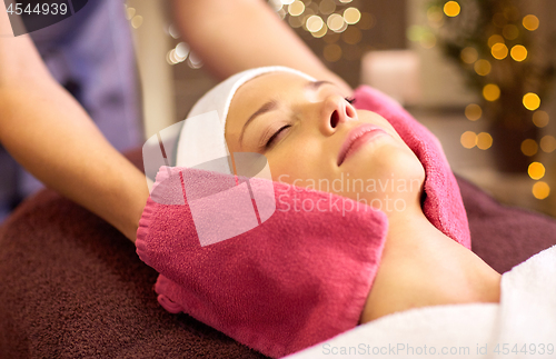 Image of woman having face massage with terry gloves at spa