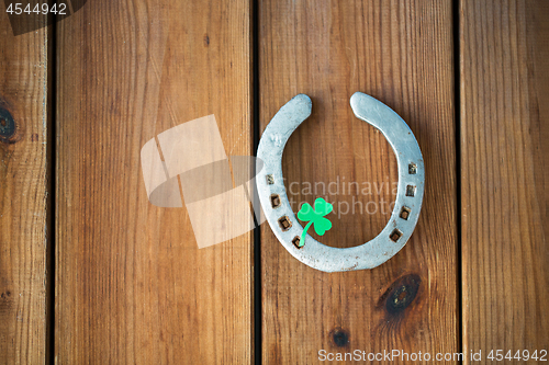 Image of horseshoe with shamrock on wooden background