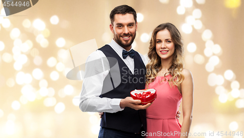 Image of happy couple with chocolate box in shape of heart