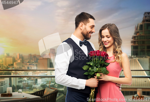 Image of happy couple with red roses over restaurant lounge