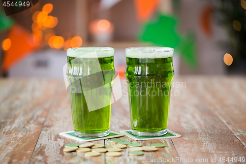 Image of glasses of green beer and gold coins on table