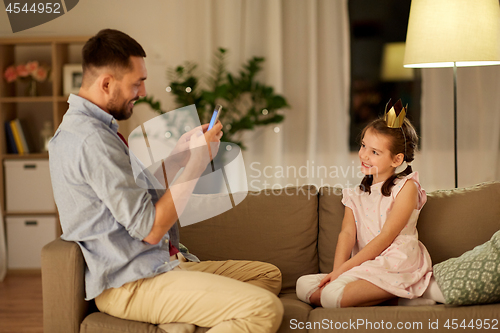 Image of father photographing daughter by cellphone at home