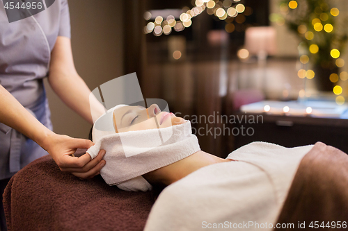 Image of woman having face massage with towel at spa parlor