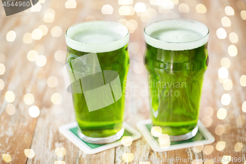 Image of two glasses of green beer on wooden table