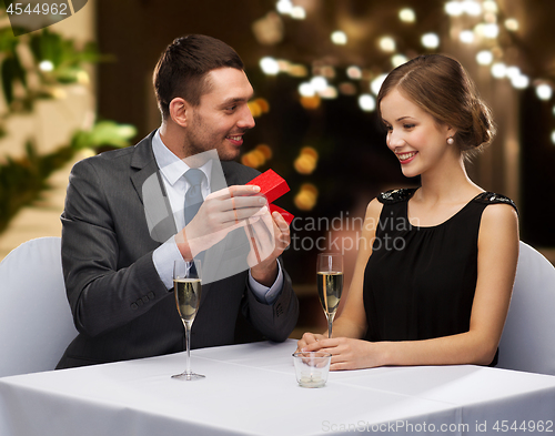 Image of man showing woman present in red box at restaurant
