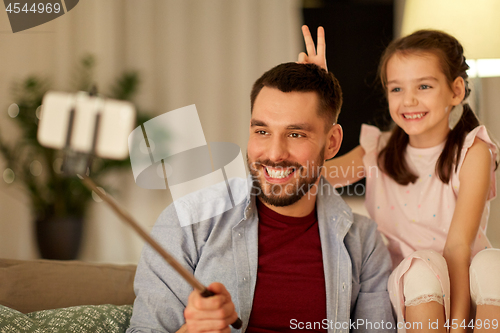 Image of father and daughter taking selfie at home