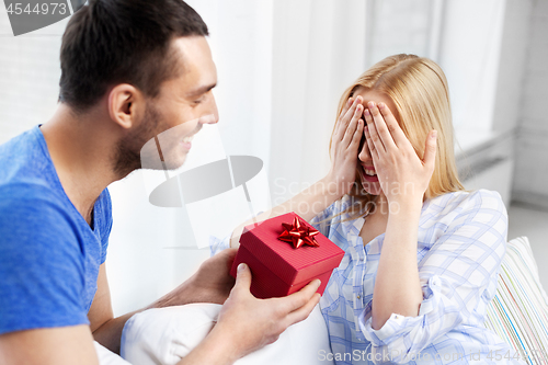 Image of happy couple with gift box at home