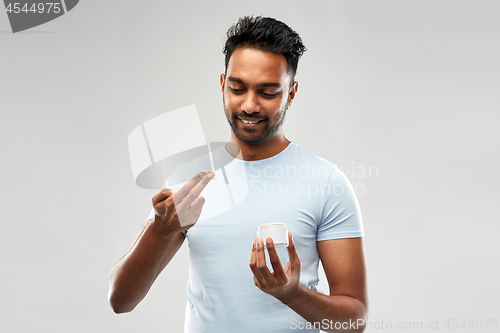 Image of happy indian man applying cream to face