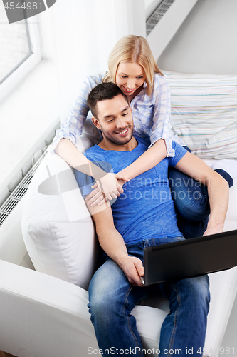 Image of happy couple with laptop computer at home