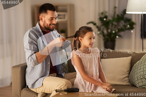 Image of father braiding daughter hair at home