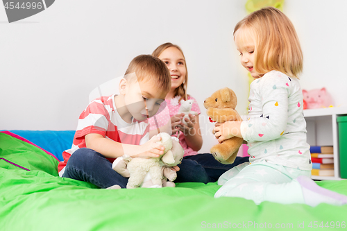 Image of happy children playing with soft toys at home