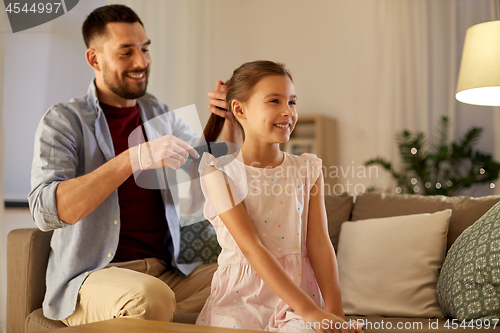 Image of father brushing daughter hair at home