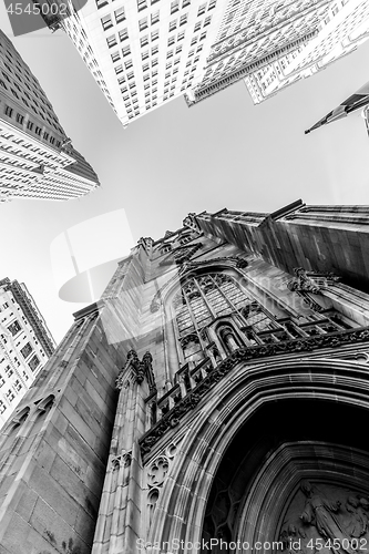 Image of Wide angle upward view of Trinity Church at Broadway and Wall Street with surrounding skyscrapers, Lower Manhattan, New York City, USA