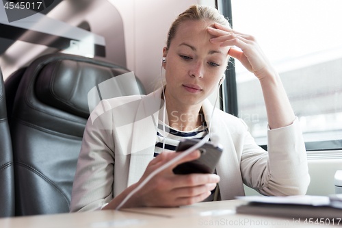 Image of Businesswoman communicating on mobile phone while traveling by train.