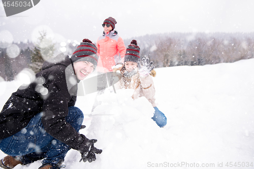 Image of group of young people making a snowman