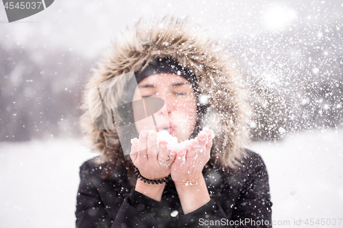 Image of young woman blowing snow on snowy day