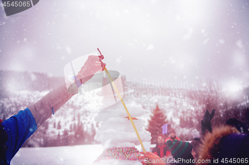 Image of young people measuring the height of finished snowman