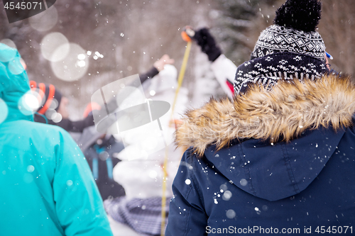 Image of young people measuring the height of finished snowman