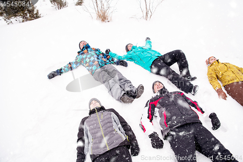 Image of group of young people laying on snow and making snow angel