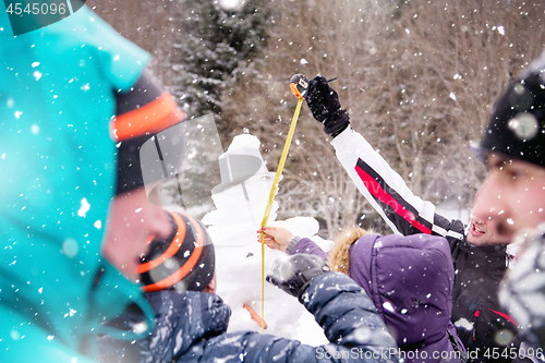 Image of young people measuring the height of finished snowman