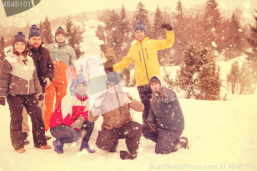 Image of group portait of young people posing with snowman