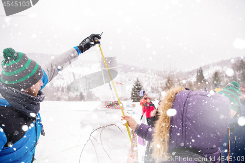 Image of young people measuring the height of finished snowman