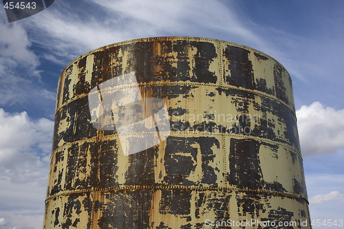 Image of old rusty grain bin against partially cloudy sky