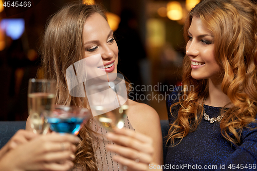 Image of happy women clinking glasses at night club