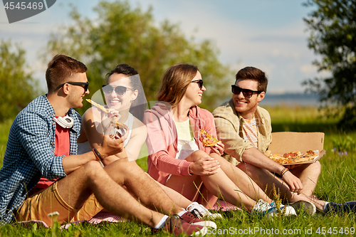 Image of friends eating pizza at picnic in summer park
