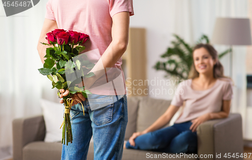 Image of woman and man with bunch of roses behind his back