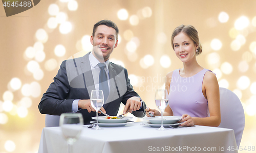 Image of smiling couple eating appetizers at restaurant