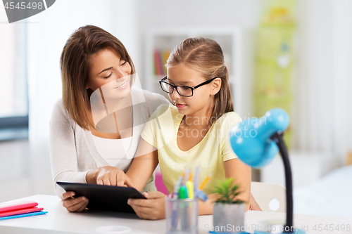 Image of mother and daughter with tablet pc doing homework