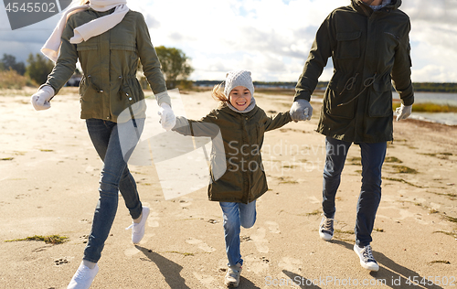 Image of happy family running along autumn beach