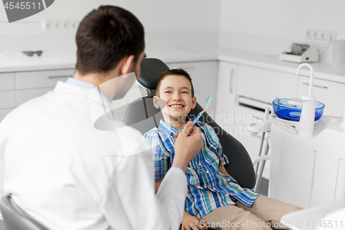 Image of dentist giving toothbrush to kid patient at clinic