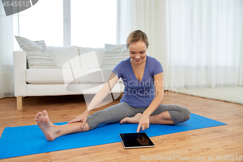 Image of woman with tablet computer doing yoga at home