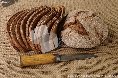 Image of slices and  loaf of rye bread and finnish knife puukko on burlap