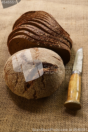 Image of slices and  loaf of rye bread and finnish knife puukko on burlap