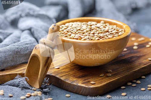 Image of Dry brown lentils in a wooden bowl.