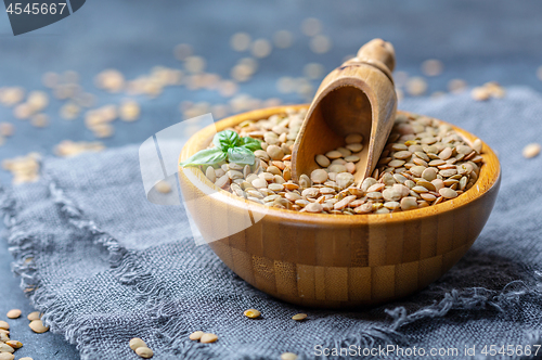 Image of Brown organic dried lentils in a wooden bowl.